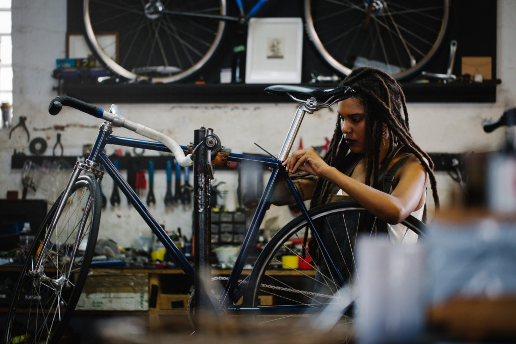 a woman fixing a bicycle in a repair shop